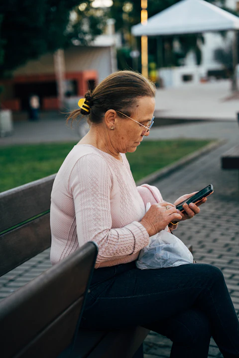 A woman on a park bench reading a message on her phone