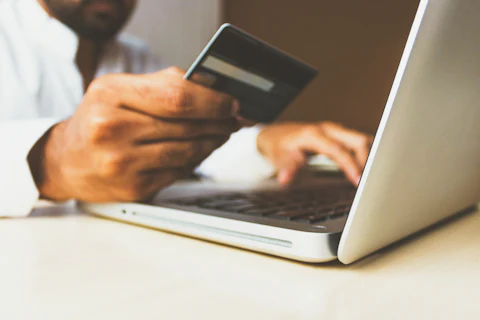 Someone holding a bank card while using a laptop