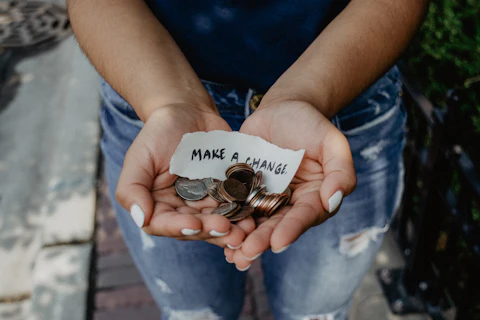 Cupped hands holding coins and a small note