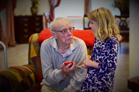 A grandfather and his granddaughter looking at a phone together