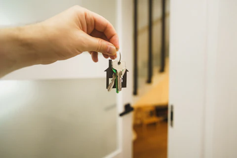 A hand holding up a house key by a front door