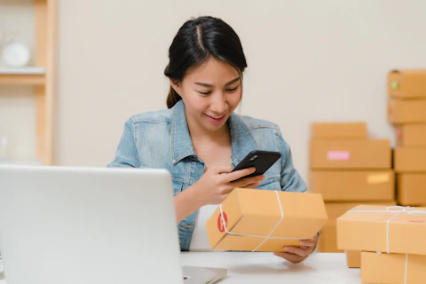A woman checking an order on her phone, with parcels around her