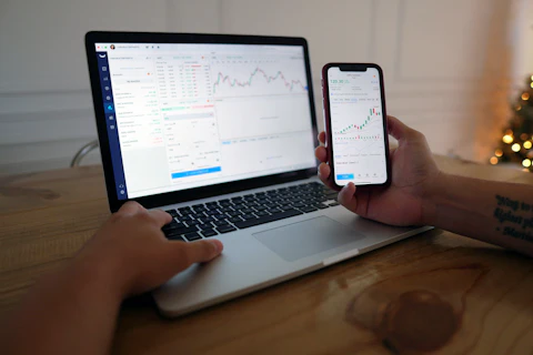 A phone showing a price chart next to a laptop